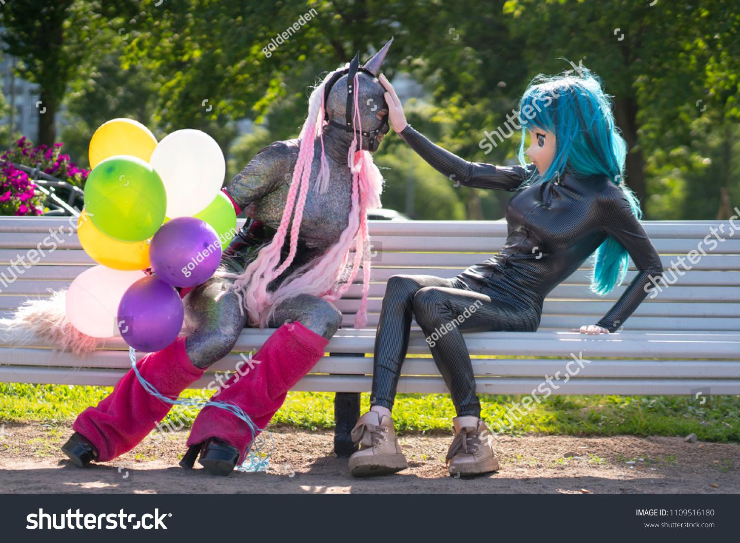 A cool yet strange stock photo from shutterstock of an anime girl pushing away someone dressed as a unicorn holding balloons. 