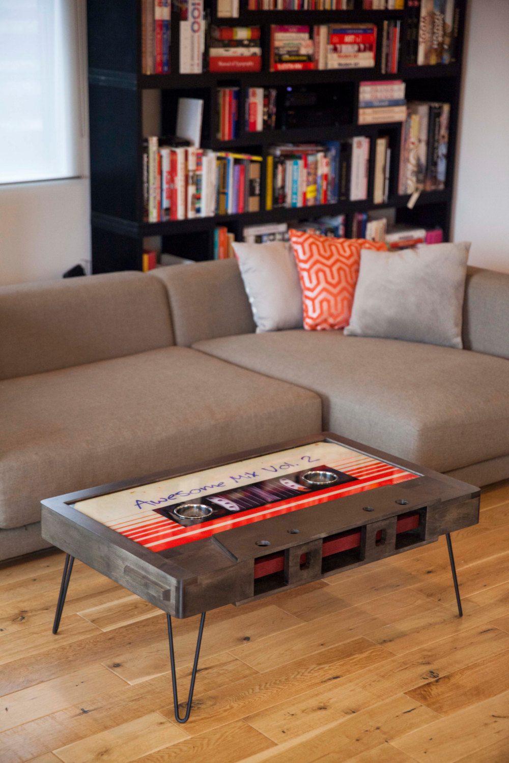 coffee table made out of oversized cassette tape prop in a stylish apartment with hardwood floors and a fully stocked book case