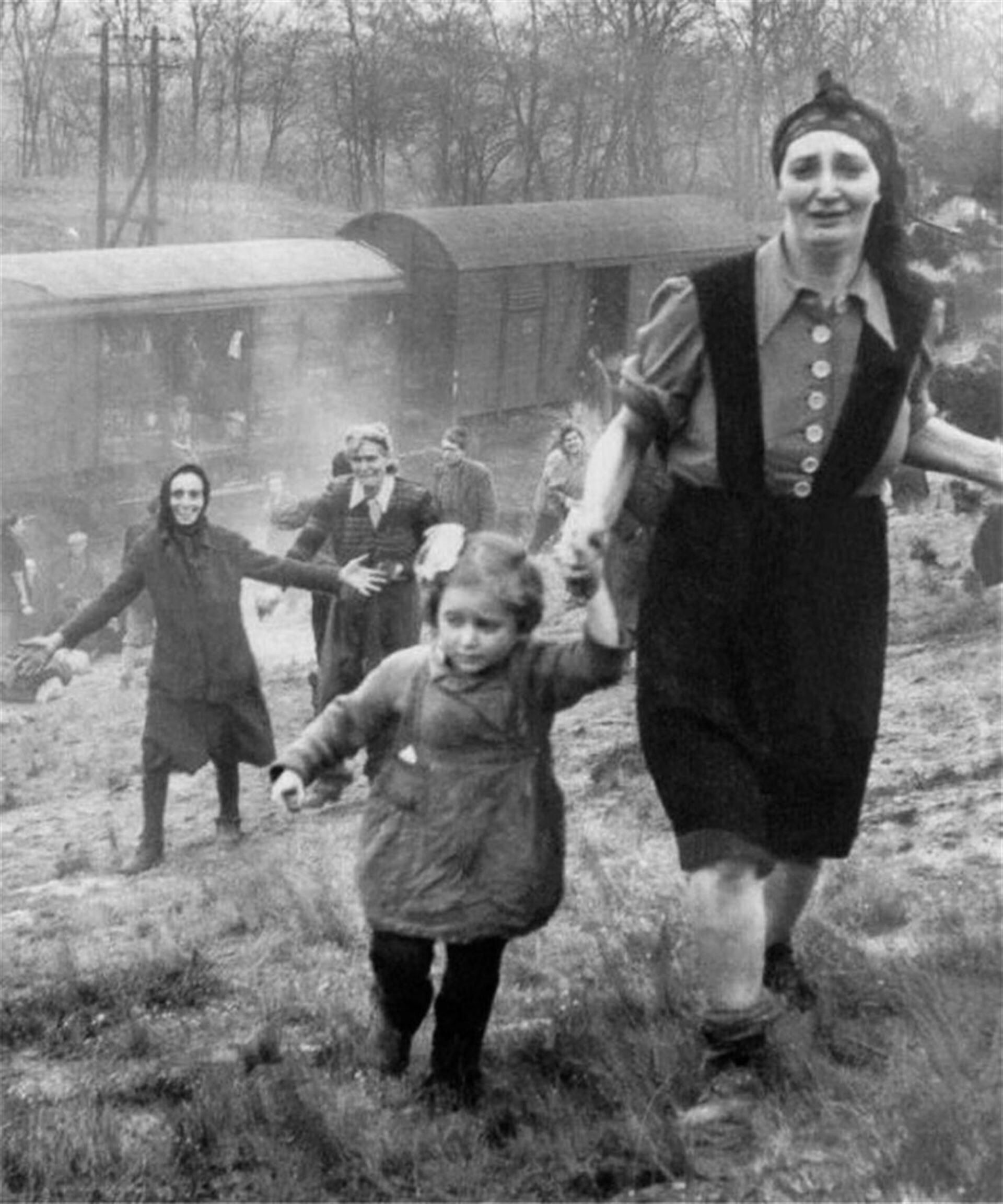 Jews being liberated from a death train in April 1945 being sent to Bergen-Belsen. The woman staring at the camera sobbing as she runs with her daughter, and the woman who is grinning for her live being saved, makes it an emotional picture.