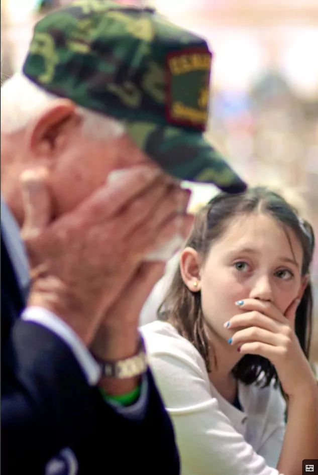 A young girl feels the emotion and passion of her grandfather as he weeps during a Veteran's Day Celebration.