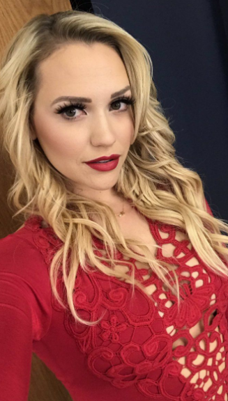 Mia Malkova in a red sleeved dress and red lipstick.