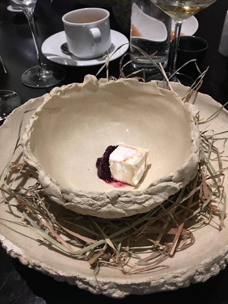 Capriole cheese with blueberries in dried clay on top of a bed of hay