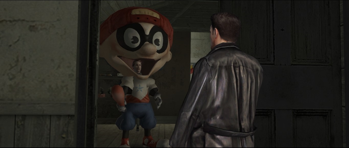 A guy with short dark brown hair and black leather jacket is standing back towards the camera. He is looking towards a guy wearing an inflatable Captain BaseBallBat-Boy costume.