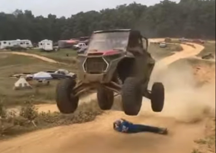 A man jumping his offroad vehicle over his dear friend. 