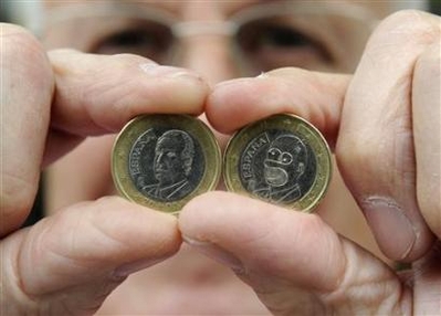 Candy shop owner Jose Martinez shows an official Spanish 1 Euro coin with the face of Spanish King Juan Carlos L and another one altered to look like a face of cartoon character Homer Simpson in the northern Spanish town of Avile August 8, 2008. Martinez found the Homer Simpson coin in his shop's cash register while counting the days' transactions 