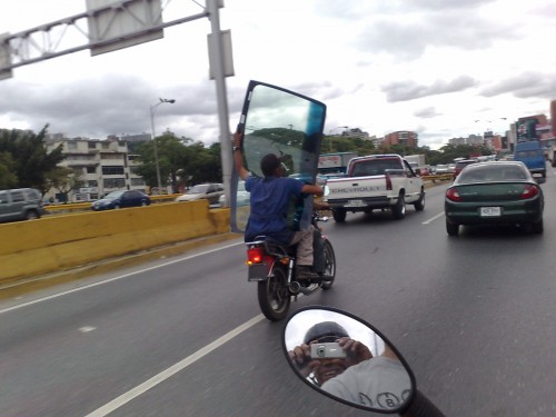 guys transporting a windshield on a scooter bike
