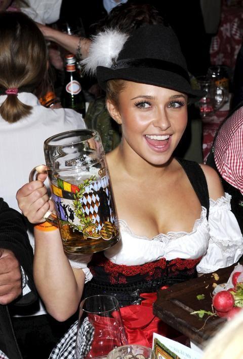 Hot girl at Oktoberfest holding up a beer and wearing a hat
