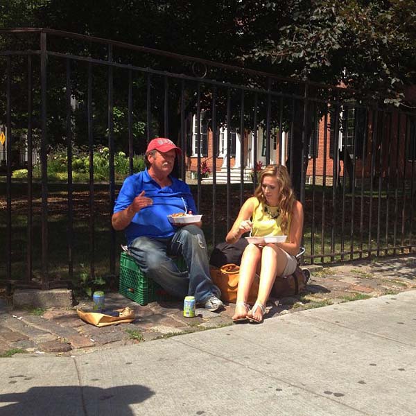 This woman buys two meals from a street vendor, and has lunch with this homeless man.