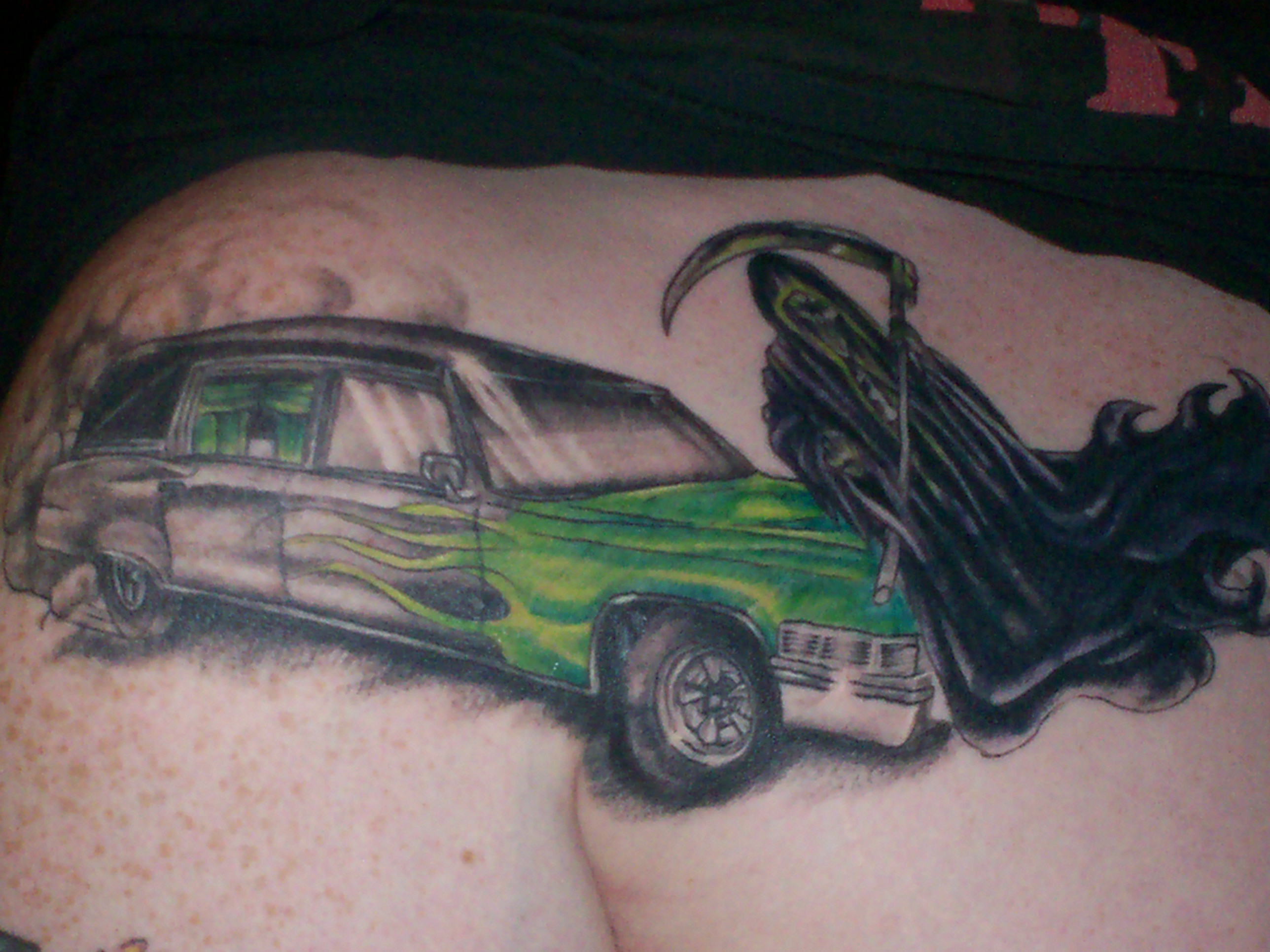 grim reaper flipping you off in front of a black hearse with green flames this tatt. was a cover up job. one of my favorite tattoos. its on my right shoulder