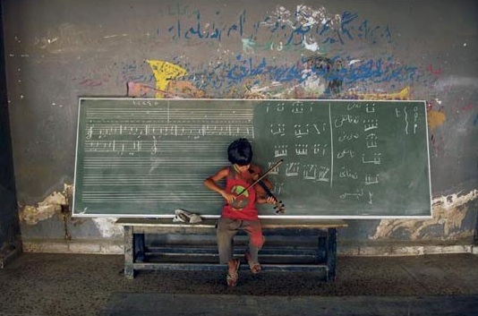 a student attempts to leatn the violin in a small, war-torn village 160 miles northeast of Baghdad