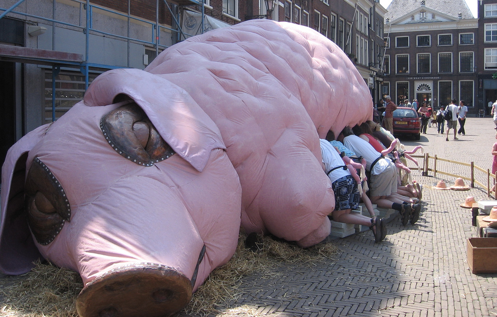 A giant balloon pig with people wearing pig tails suckling from its teat. Why would anybody think this looked like fun?