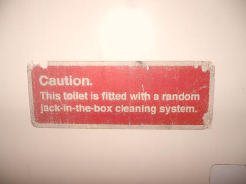 sign - Caution. This toilet is fitted with a random jackinthebox cleaning system.