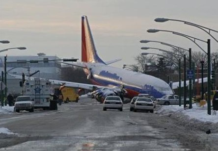 Picture of a plane that slipped off the tarmac and out onto city streets blocking traffic.