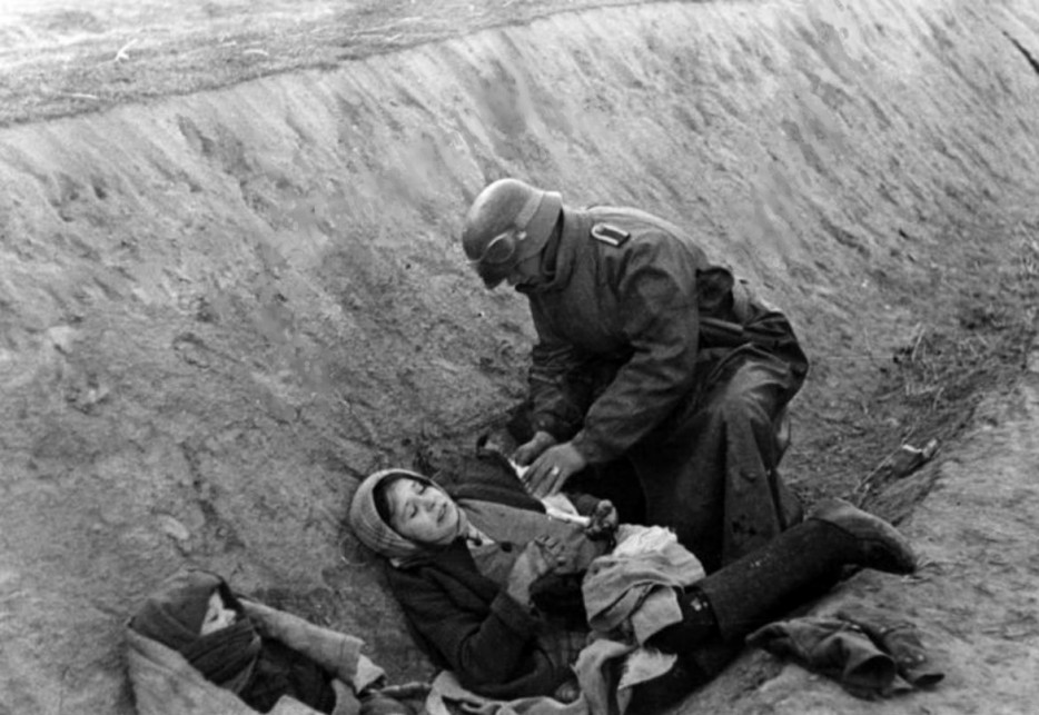 A German soldier applies a dressing to a wounded Russian civilian. World War II, c. 1941