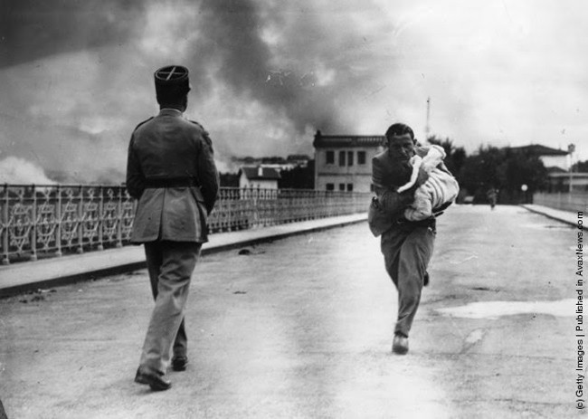Journalist Raymond Walker rushes across a bridge into France with a child that he saved from the Spanish Civil War. 1936