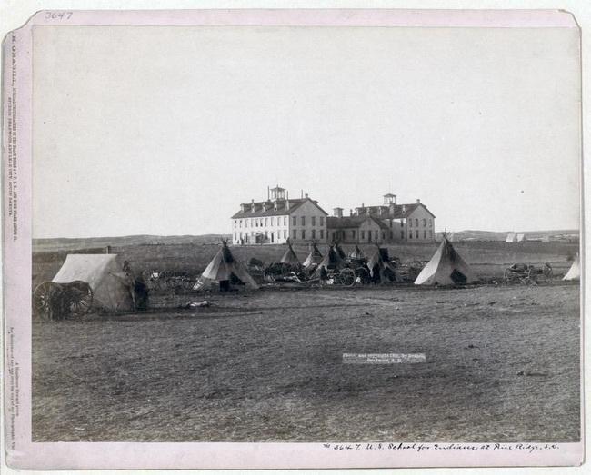 Several Teepees In View Of Two Large Homes In Pine Ridge, South Dakota
