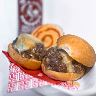 Sausage Sister's Sriracha Sliders.  “Great Balls of Fire” meatballs with Monterey Jack cheese at the center, served on a crusty slider bun with Sister’s Sweet ‘n’ Hot Sriracha Sauce