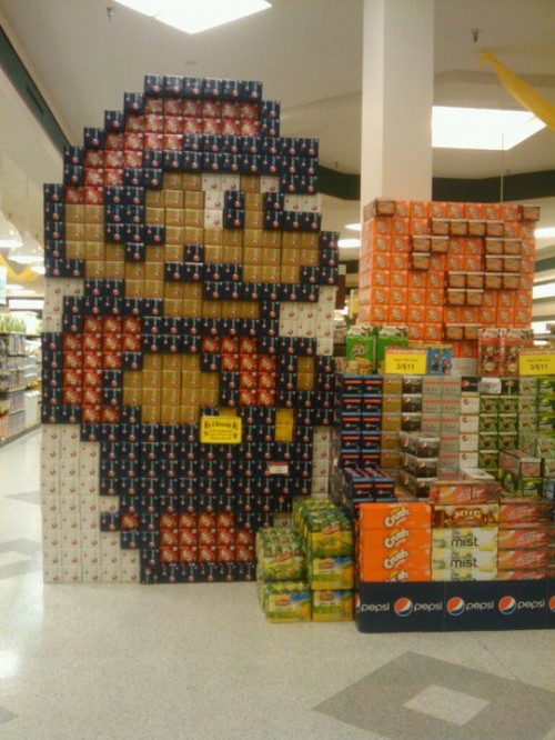 A supermarket display made out of soda boxes in the shape of Mario.