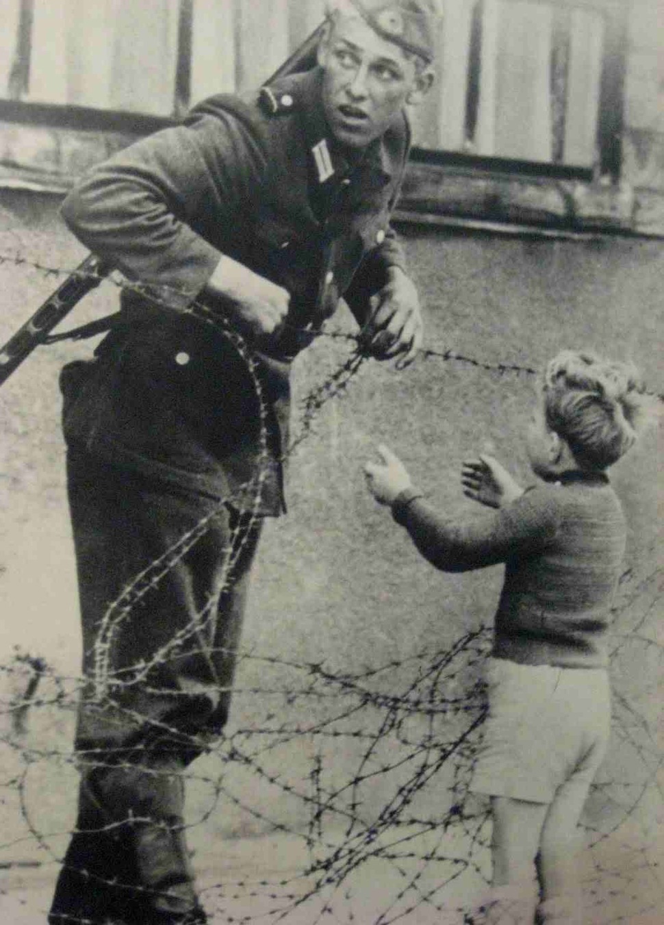 east german soldier helps a little boy sneak across the berlin wall