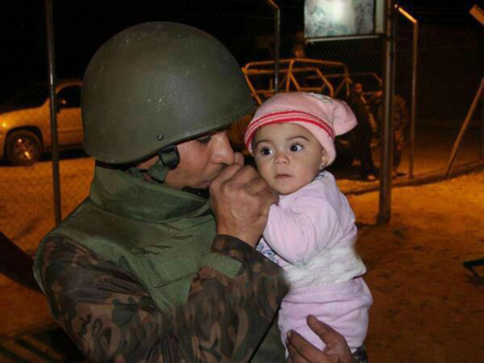 A Jordanian soldier warms the hands of a Syrian baby evacuated from the country. Syrian Civil War, c. 2013