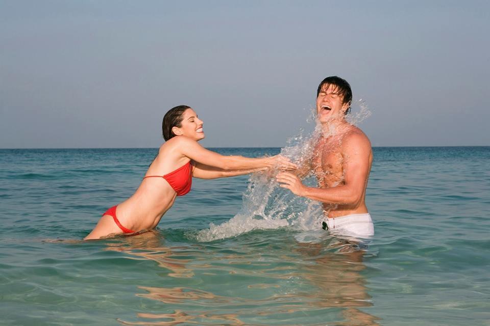 A cute young couple playing in the sea.
