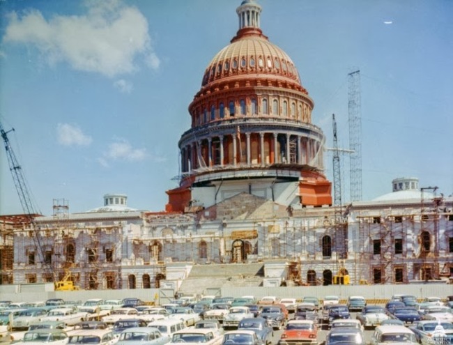 The US Capitol Building is painted with a layer of red anti-rust paint, before being painted white again. [1959]