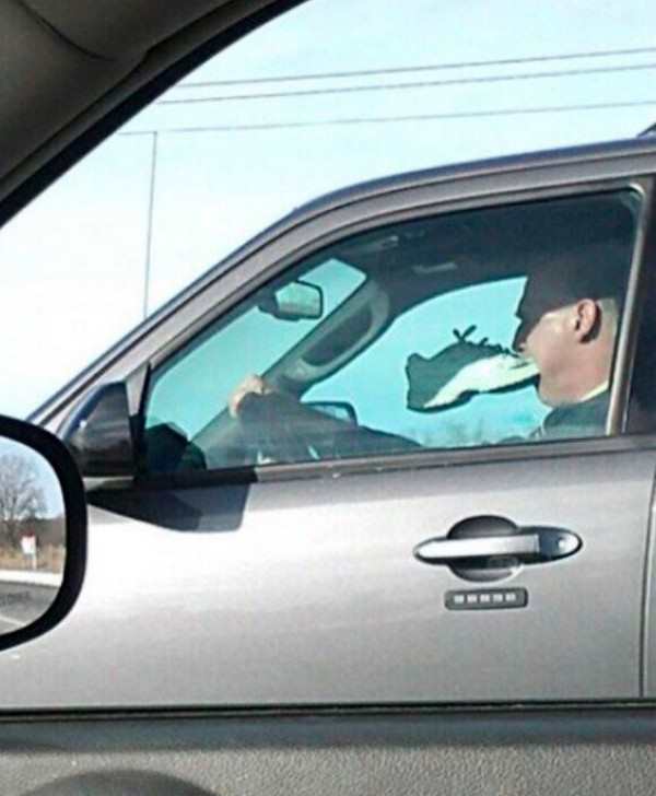 guy driving with shoe in mouth