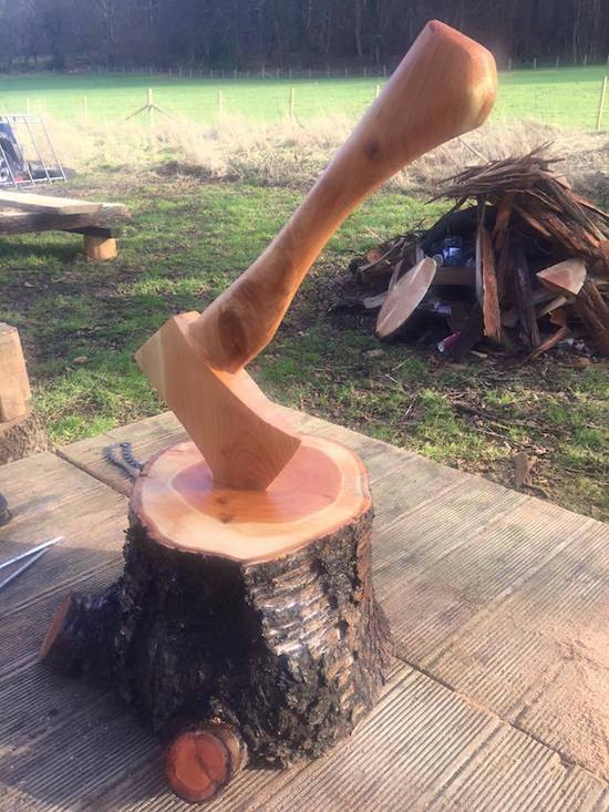 Wooden carving of an ax in a stump of wood.