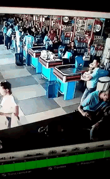 GIF of security footage of a man who drops a can of food at the checkout and kicks it in a controlled fashion that allows him to regain control of the product.