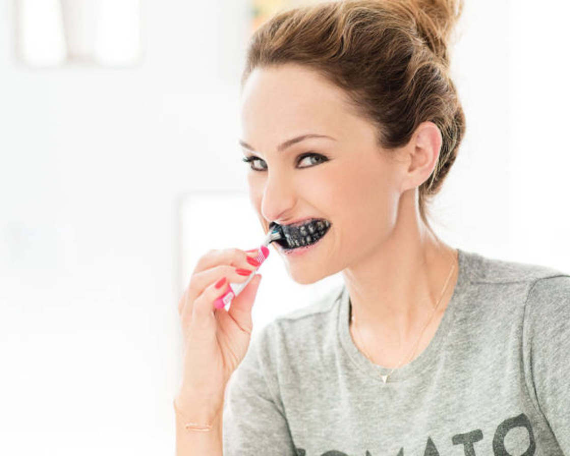 Girl brushing her teeth with black toothpaste.