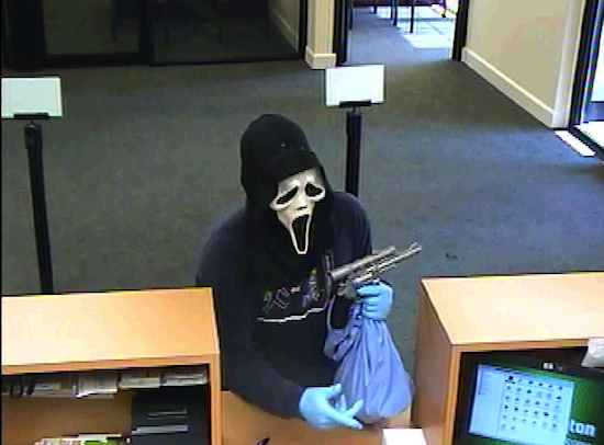 Man in scream mask that looks like he is robbing the place