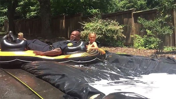 Officer Joe Jones slides down in an inner tube with one of the neighborhood kids.