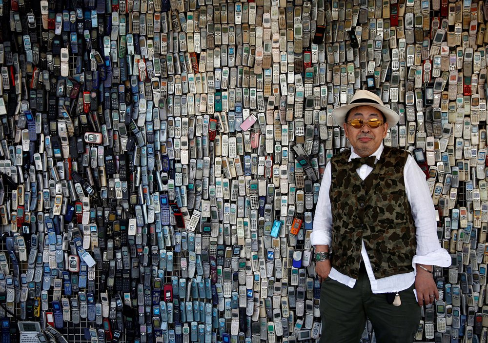 Chinese man in vest selling a wall of cell phones