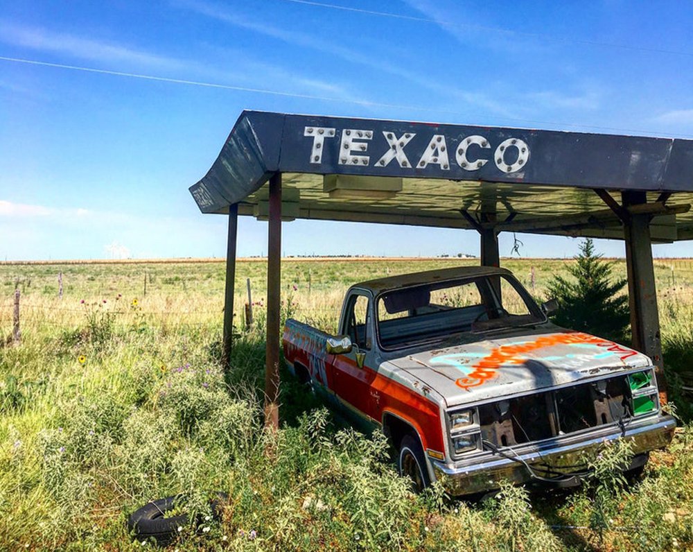 Old pickup truck laying to waste at a defunct Texaco gas station.