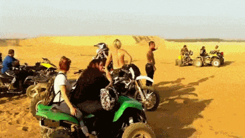 GIf of dude riding up a steep cliff in a quad-bike, and he lands on his feet at the top as the quad-bike rides away.