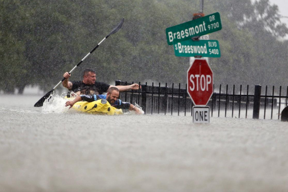 People Kayaking past flooded stop signs from Hurricane Harvey