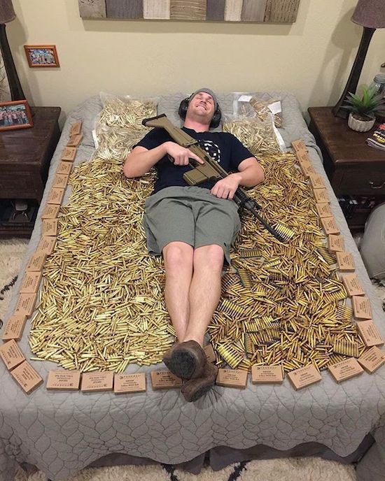 Man with his gun lying on a bed of ammo.
