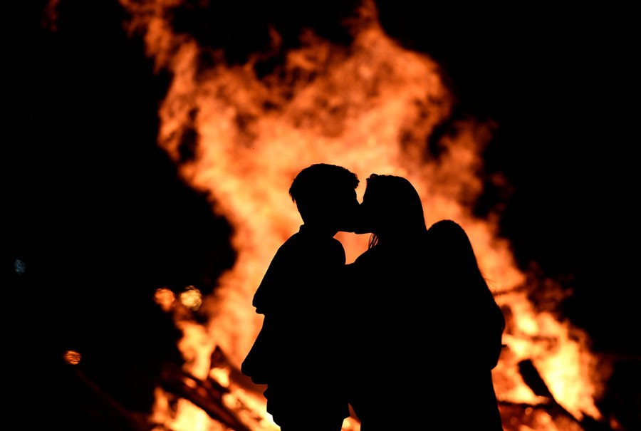 A couple kisses next to a bonfire on the Poniente beach celebrating the summer solstice in Gijon, Spain, on June 24, 2017.