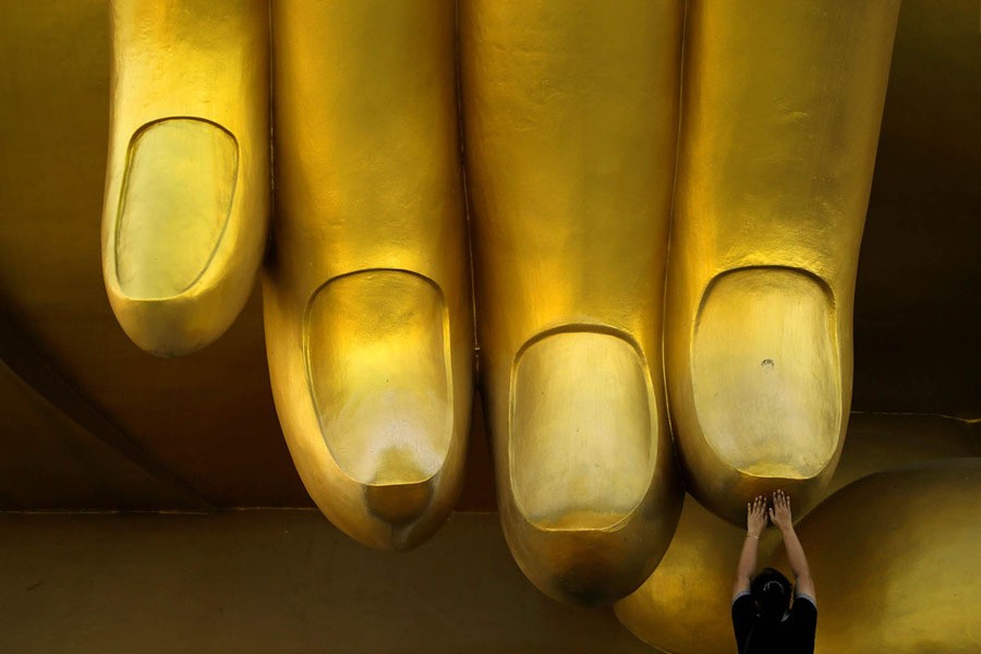 A woman prays while touching the fingers of a Buddha statue during the annual Makha Bucha Day—which celebrates Buddha's teachings—in Ang Thong, Thailand, on February 11, 2017.