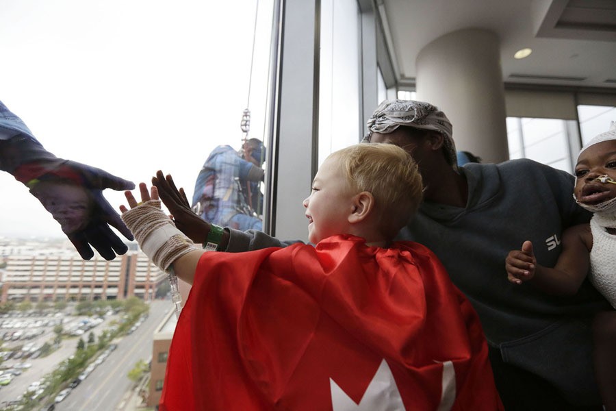 Bettina Billups, right, helps Brentley Lashum, 2, touch Superman's hand during superhero window-washing day at Children's of Alabama, as part of the hospital's Superhero Month celebrations, on October 11, 2017, in Birmingham, Alabama.