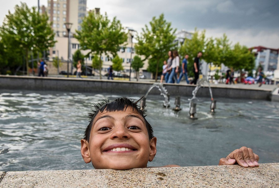 Children of the Roma community play as they cool off in a fountain in the main square of Pristina, Kosovo, on June 14, 2017.