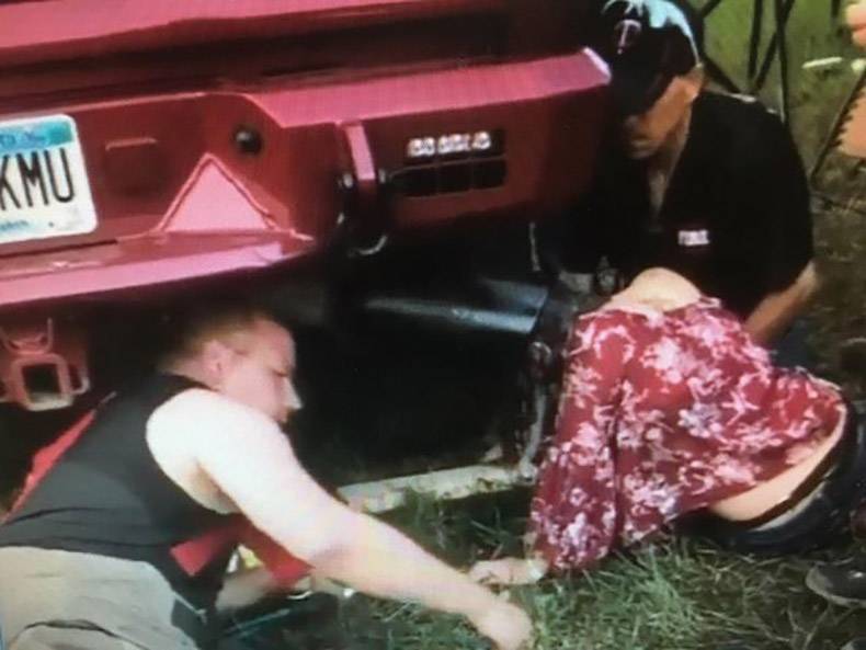 Car jacked up with woman putting her head in the exhaust pipe