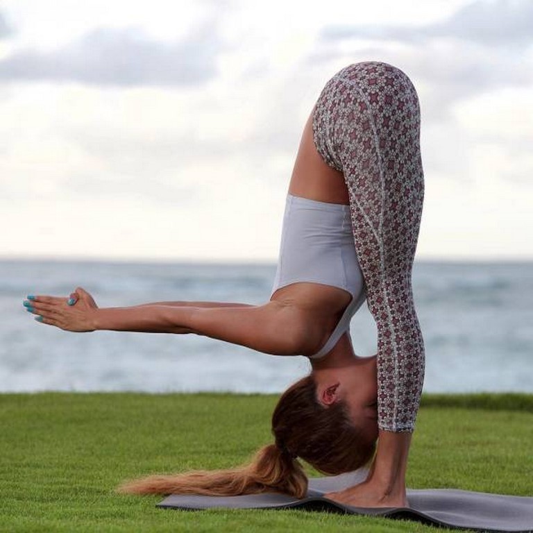 woman doing great yoga stretch by the sea side