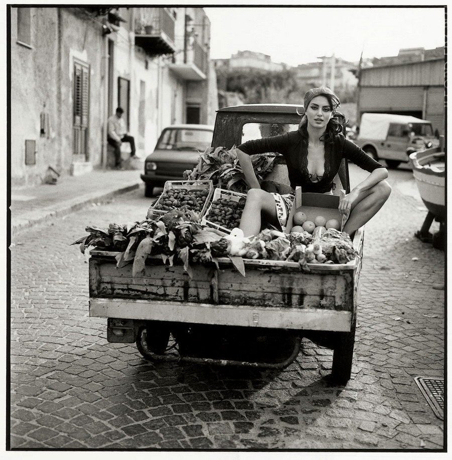 Beautiful woman in the back of a truck surrounded by vegetables