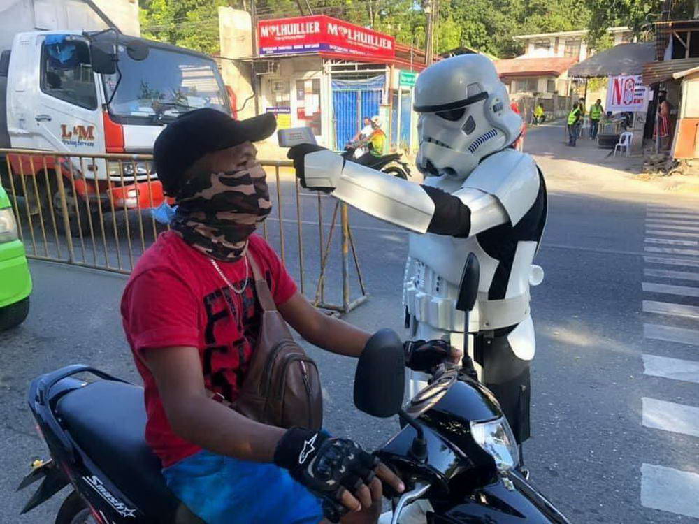 man getting his temperature checked on street by person in storm trooper costume