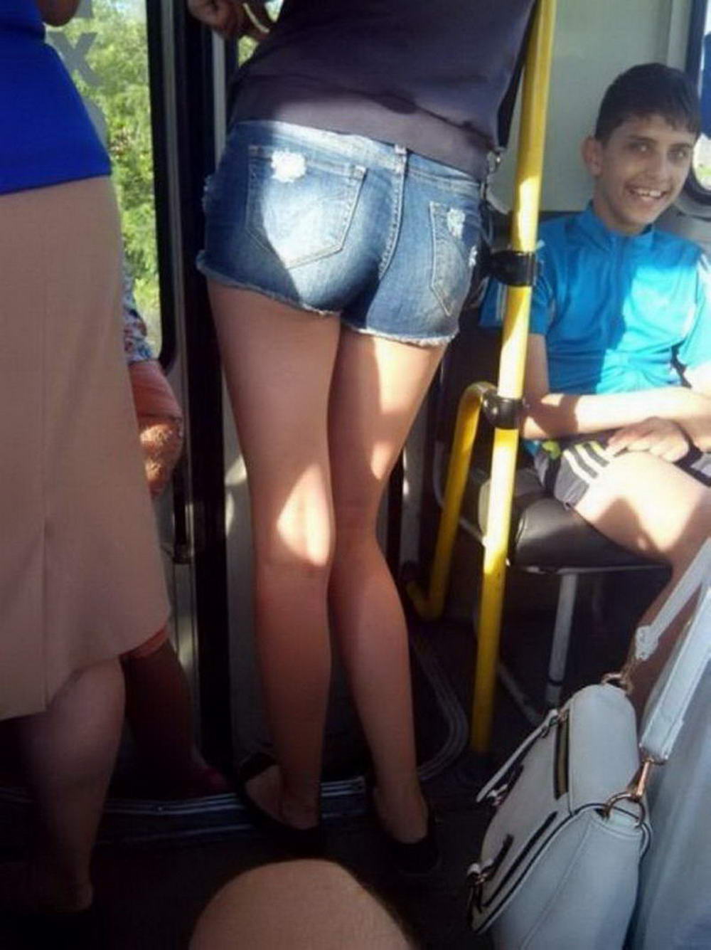 kid on bus smiling about women standing next to him