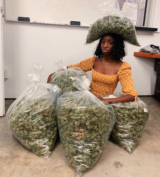 girl surrounded by huge bags of marijuana