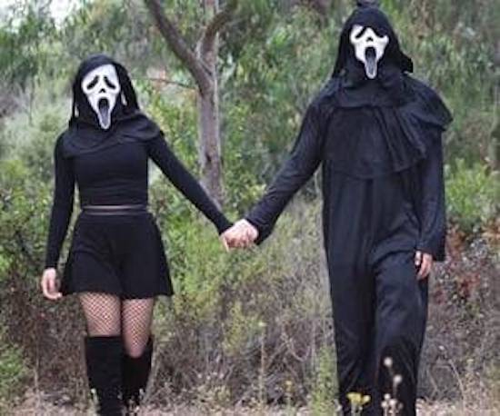 couple wearing Scream masks holding hands
