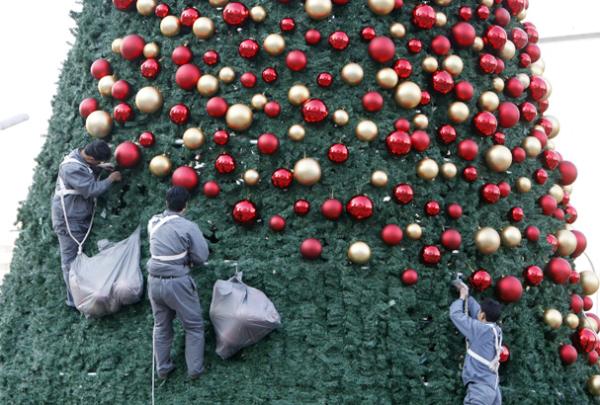  Workers decorate a Christmas tree outside a shopping mall in central Beijing Friday, Nov. 21, 2008. Though not a tradition in China, Christmas has been seized upon by retailers who use it as a way to encourage gift giving, and the accompanying boost in sales. (AP Photo/Greg Baker) 