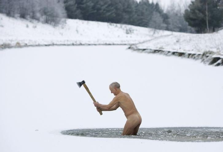 old naked man in ice pond with an axe